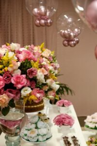 Beautiful pink and white rose arrangement with decorative balloons on display for a celebration.